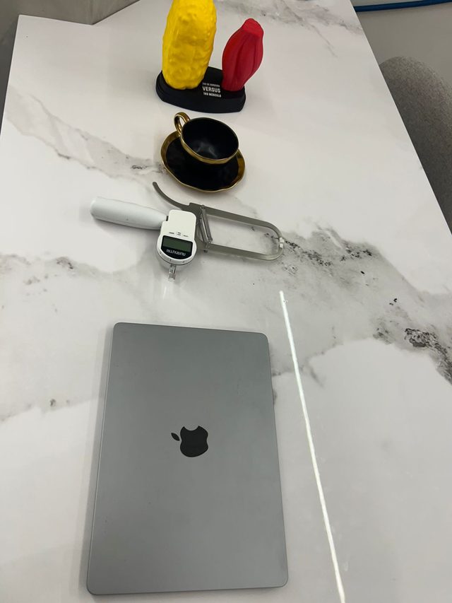 Mesa de mármore com adipômetro digital e modelos anatômicos comparando um quilo de gordura e um quilo de músculo